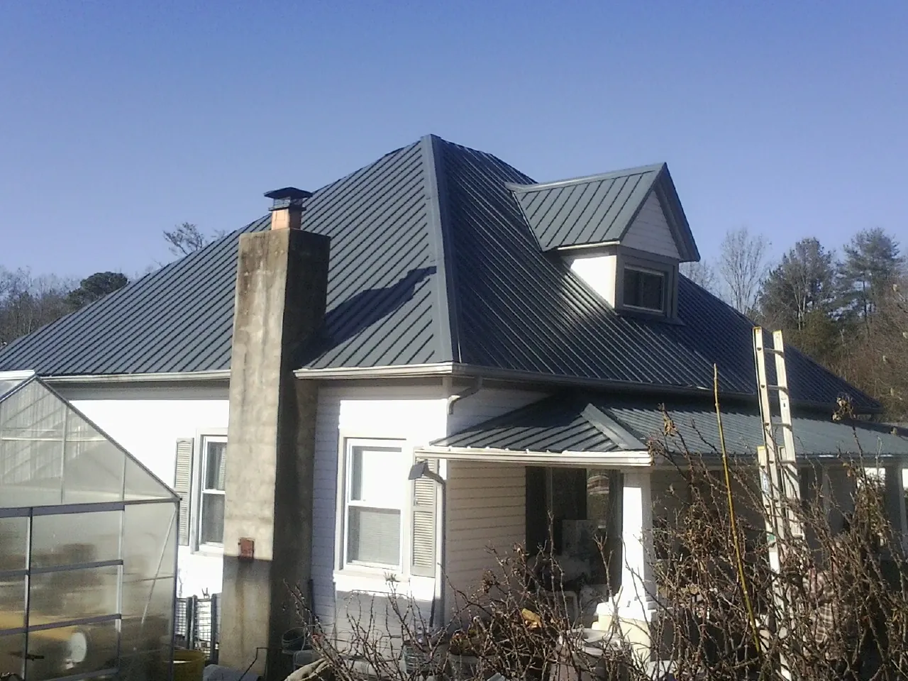 Dark blue standing seam metal roof on a white farmhouse with dormer — Slate & Tile Roof Repair by Roofing Brothers in Congerville