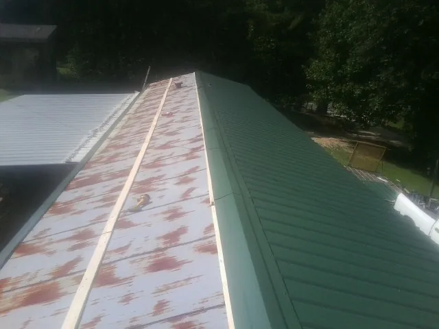 Old rusted panels beside newly installed green metal roofing — Wind Damage Roof Repair by Roofing Brothers in Congerville