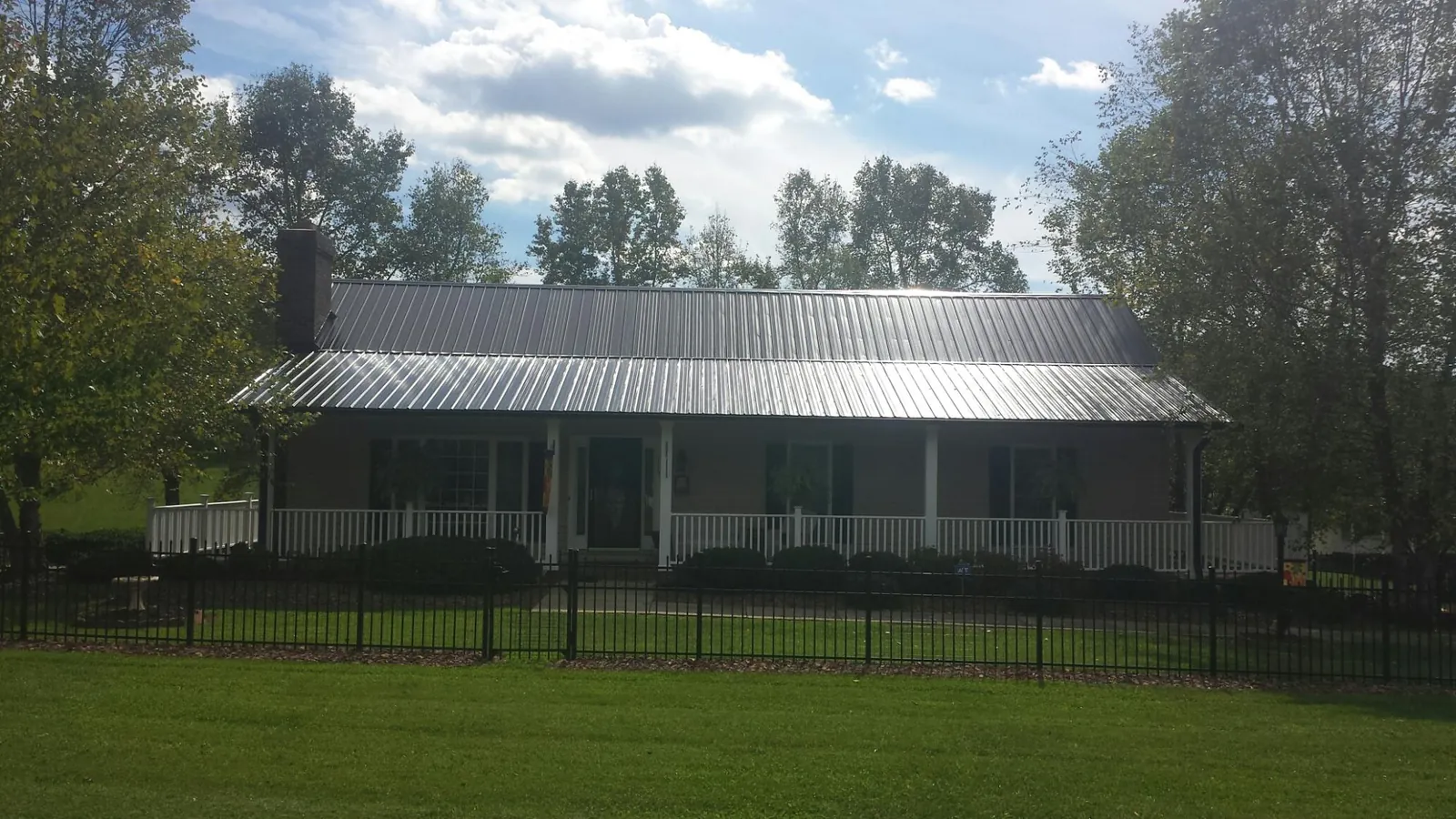 Gray metal roof on a brick ranch with a full width front porch — Gutter Guard Installation work by our crew in Congerville