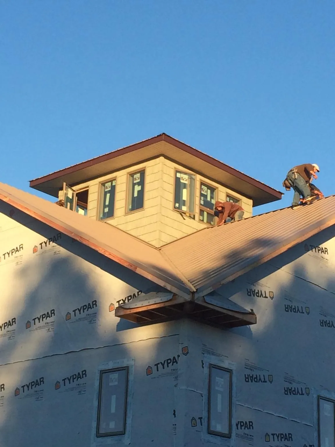 Roofers working around a rooftop cupola on a new metal roof at sunset — Roof Waterproofing in Congerville by Roofing Brothers